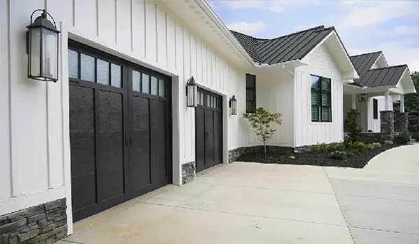 Carriage house style black garage door white house